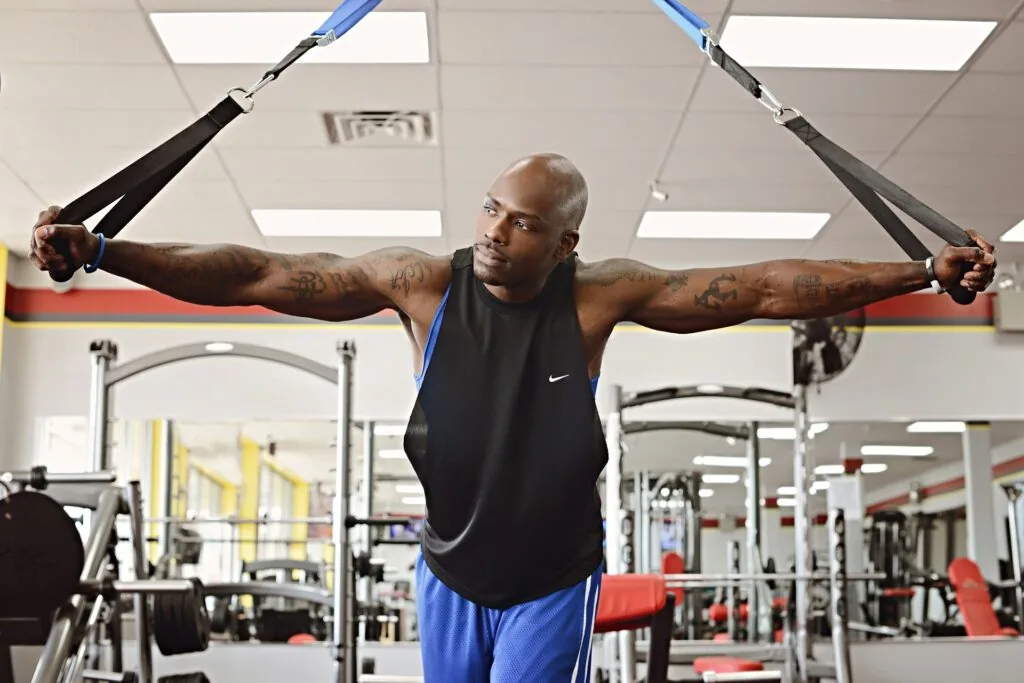 Man performing suspension strap exercise with arms extended in gym setting