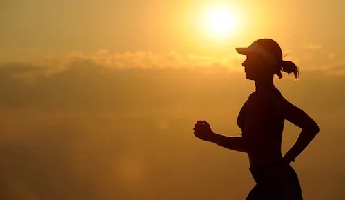 Silhouette of person jogging at sunset against golden sky